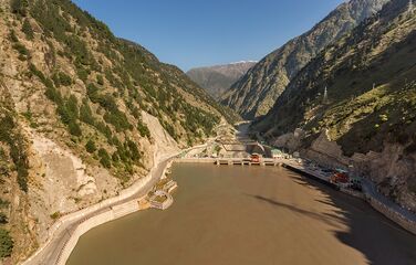 Wasserkraftwerk in einem Tal zwischen bewaldeten Bergen